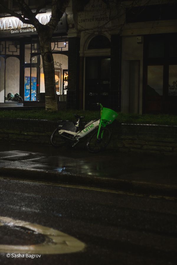 A photo of a lime bike layed down on the sidewalk